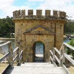 a wooden bridge leading to a stone tower